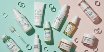 Exhibición de productos de belleza limpia con etiquetas de "libre de" y "ingredientes naturales" en un fondo luminoso.