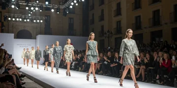 Pasarela de moda vibrante en España, con modelos y público elegante, simbolizando el dinamismo económico del sector.