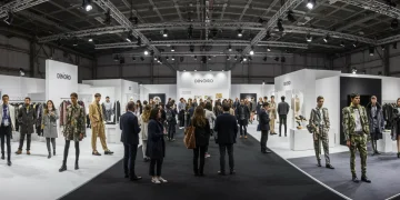 Vista panorámica de una feria de moda en España en 2025, con profesionales del sector, diseñadores y modelos interactuando en un ambiente vibrante y moderno.