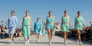 Modelos desfilando con prendas de moda sostenible fabricadas con materiales innovadores y sin plástico en un entorno urbano español futurista.