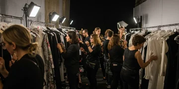 Modelos y estilistas preparándose tras bambalinas en un prestigioso evento de moda en España, reflejando la complejidad de la organización.