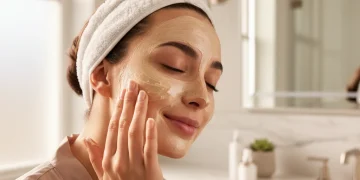Mujer aplicando mascarilla antiedad de lujo en su rostro, con piel radiante y juvenil.